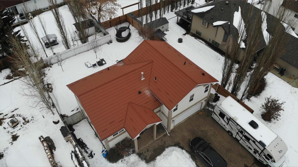 A house surrounded by snow featuring recyclable metal roofing with red tiles from I Roof