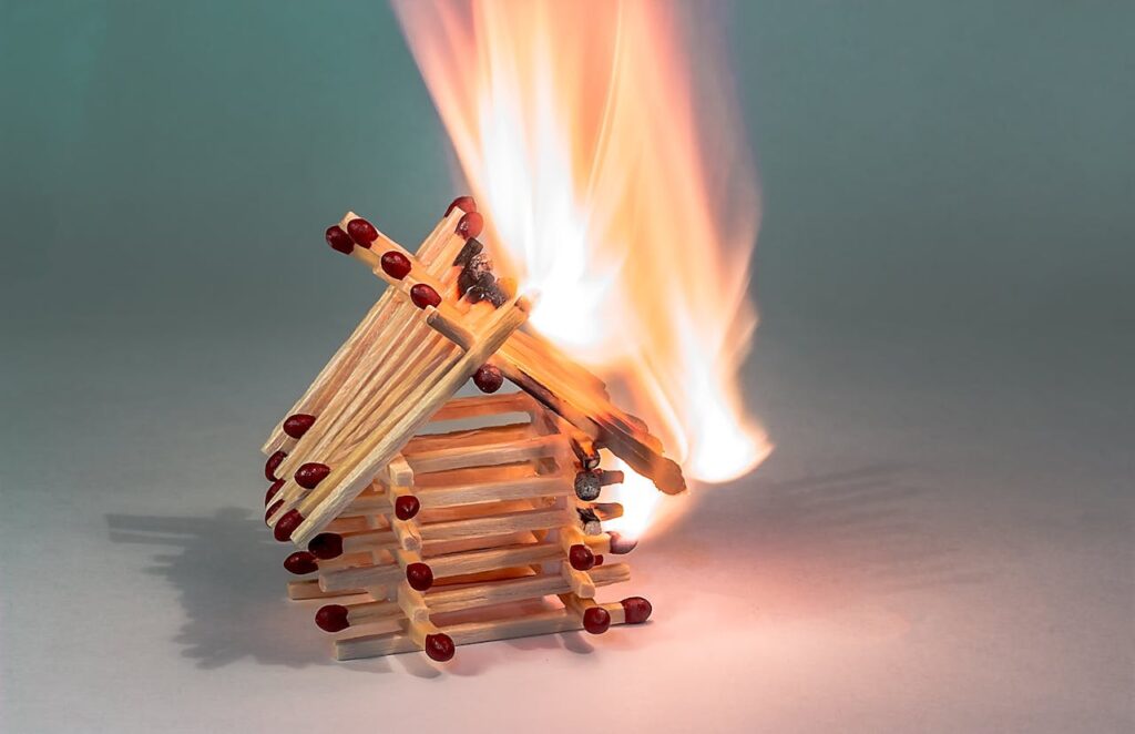 Matchsticks in the shape of a house being lit