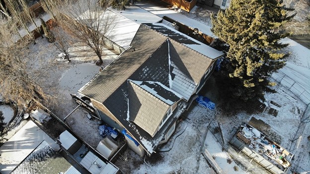 View of a house with a metal roof partially covered in snow.